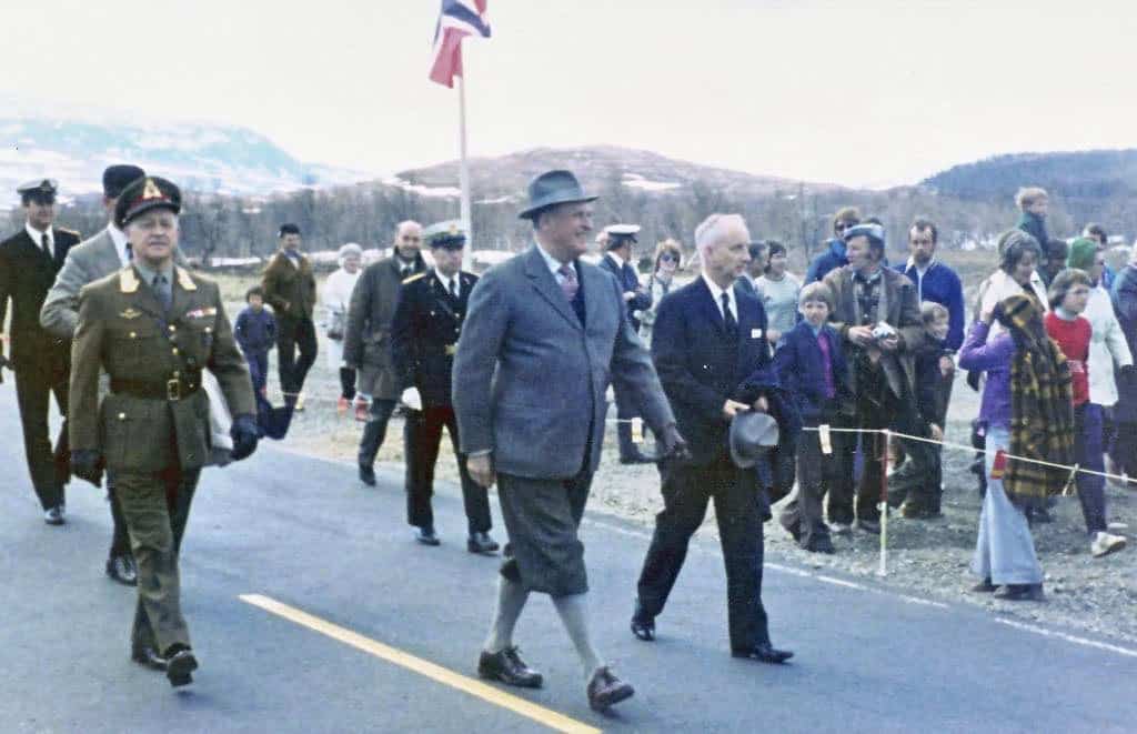 Ett foto från invigningen av Silvervägen. Kong Olav går längs vägen, omgiven av andra människor.