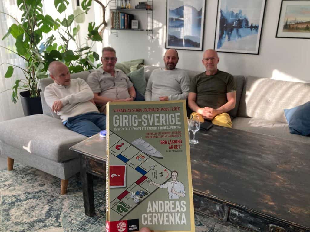 I förgrunden en pocketbok med titeln Girig-Sverige. I bakgrunden fyra män i en soffa.