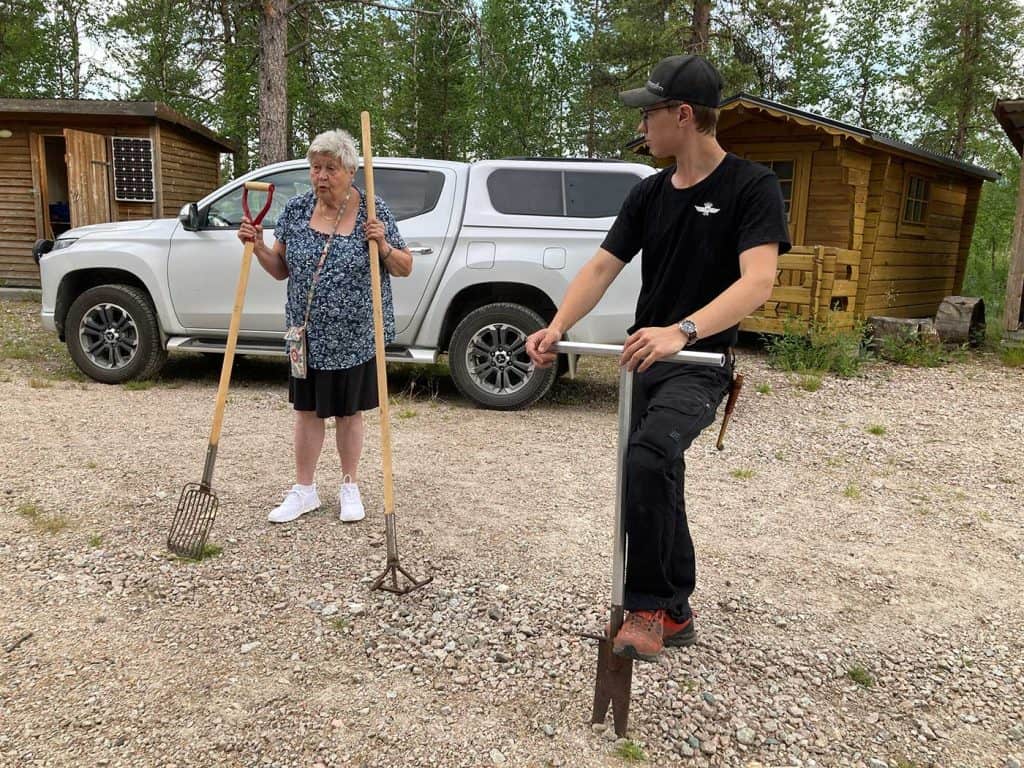 En kvinna och en man, bägge håller i redskap. 