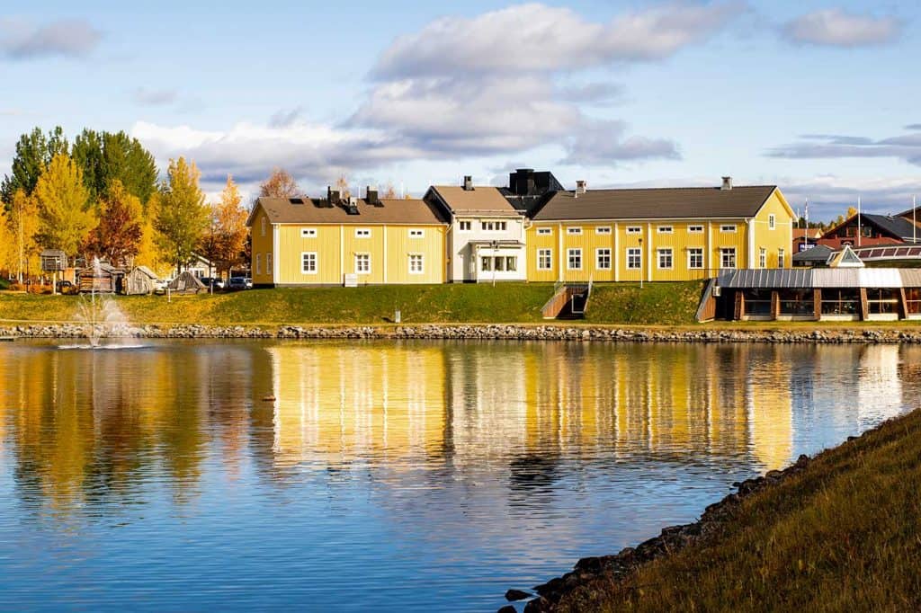 En höstbild av Silvermuseet i solsken, där det ligger vid vatten. 