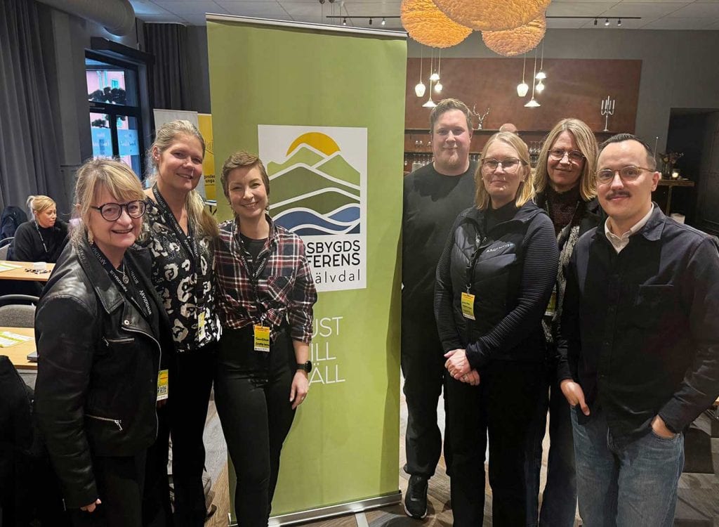 Sju glada män och kvinnor vid en roll-up-skylt med texten Landsbygdskonferens Pite älvdal