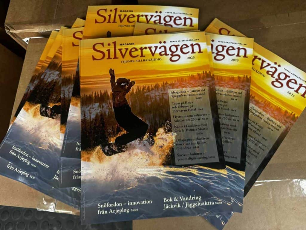 Flera tidningar i solfjädersform och i flera lager. Omslagsbilden visar en snowboardåkare som hoppar så att snön yr runt brädan och fötterna. Tidningens titel är Magasin Silvervägen. 