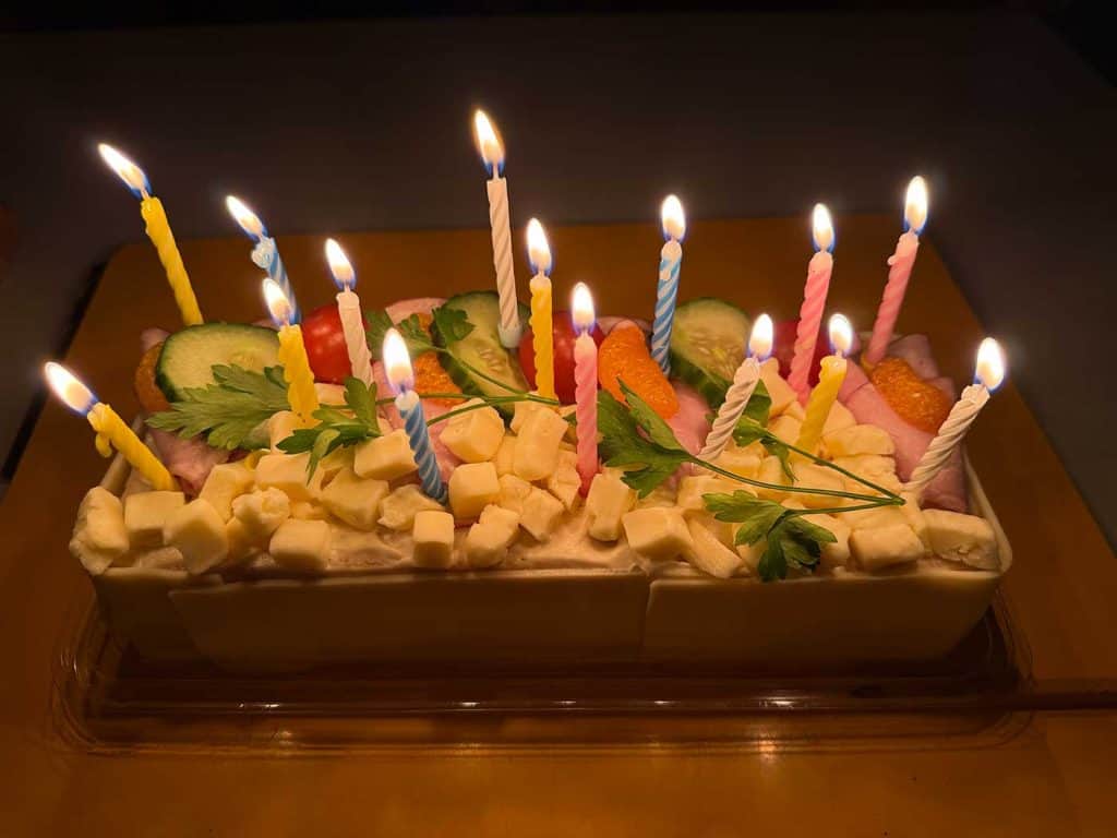 En smörgåstårta med 15 tända små stearinljus på.